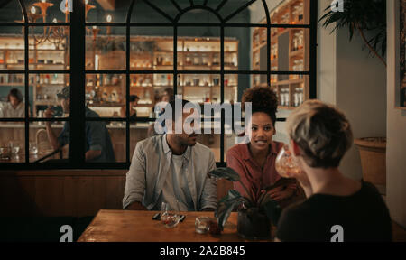 Divers friends chatting autour d'un verre dans un bar de nuit Banque D'Images