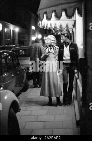 La nuit, un couple marche main dans la main à travers les rues de Munich. Banque D'Images