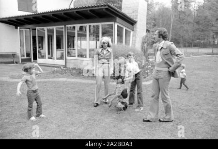 Accueil Histoire avec la famille Beckenbauer. Sur la photo : Le Beckenbauer famille joue dans le jardin avec le chien, de gauche à droite : Stephan, Brigitte Beckebauer, Thomas, Michael (derrière) et Franz Beckenbauer. Banque D'Images