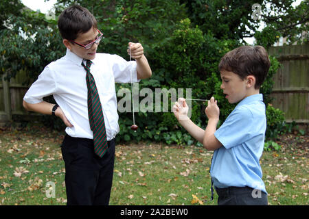 Deux enfants en uniforme d'école jouer conkers ayant une lutte à l'extérieur à l'automne de conker 2019 Banque D'Images