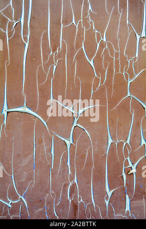 La texture de vieux film d'éclatement sur mur de béton. Film de protection fissurée rouge avec bords tordus avec blue mauvais côté. Peeling endommagées de façades, rol Banque D'Images