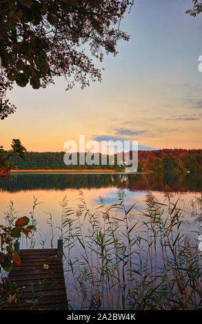 Coucher du soleil sur le quai avec maison et forêt en arrière-plan. Banque D'Images