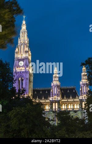 Hôtel de ville de Vienne avec illuminé par les feux jaune et violet. Tours entre les arbres en fin de soirée Banque D'Images