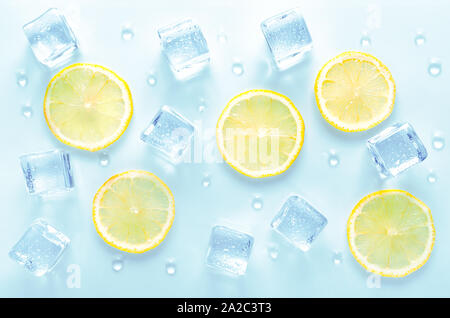 Des cubes de glace et de tranche de citron frais avec des gouttes d'eau sur fond bleu Banque D'Images