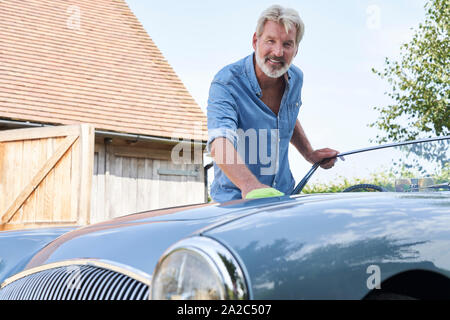 Portrait d'homme mûr restauré Polissage Voiture de sport classique dehors à la maison Banque D'Images