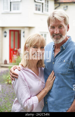 Portrait Of Mature Couple debout dans un jardin en face de maison de rêve en campagne Banque D'Images