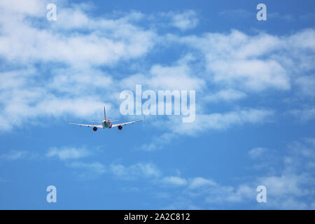 Vol d'un avion dans le ciel bleu sur fond de nuages blancs, vue arrière. Moteur deux-avion commercial pendant le virage, la turbulence et le concept de voyage Banque D'Images