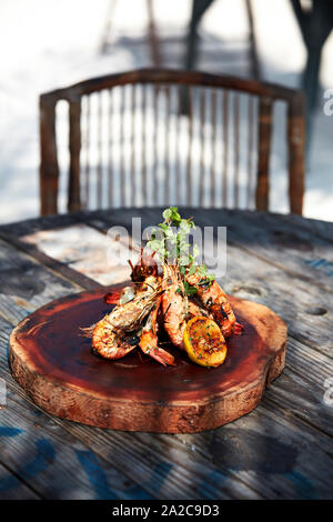 Fruits de mer frais grillés au citron et servi sur planche en bois fabriqués à la main au restaurant de plage en plein air Banque D'Images