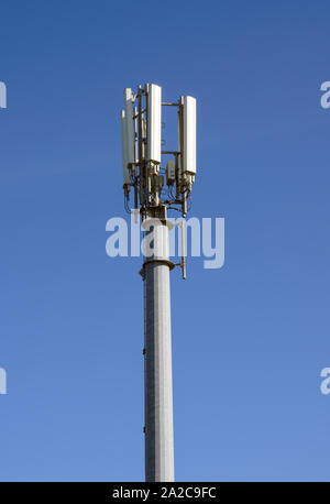 Téléphone mobile et des communications mast photographié contre un ciel bleu Banque D'Images