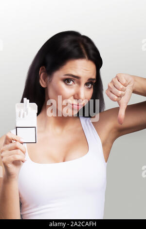 Ne pas fumer. Jeune femme belle campagne contre le tabagisme. Détient un paquet dans ses mains méprise de fumer. Le concept de la santé. Sur un fond gris Banque D'Images