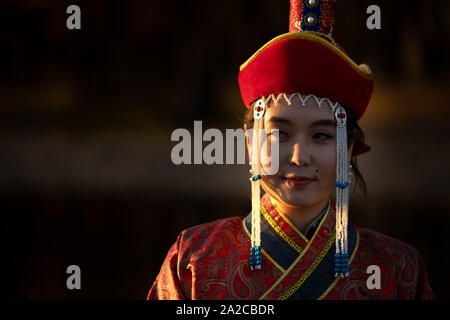 Belle jeune femme posant en robe mongole traditionnelle dans le coucher du soleil la lumière. Oulan-bator, Mongolie. Banque D'Images