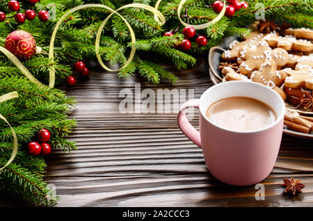 Noël arrière-plan de mug rose avec du chocolat chaud, de la direction générale de l'épinette et du bac avec gingerbread man cookies sur table en bois Banque D'Images