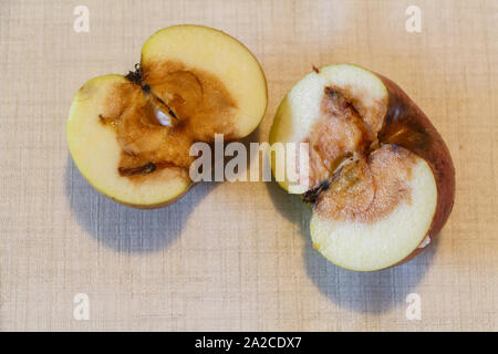 Pomme pourrie coupé en deux pièces sur une table Banque D'Images