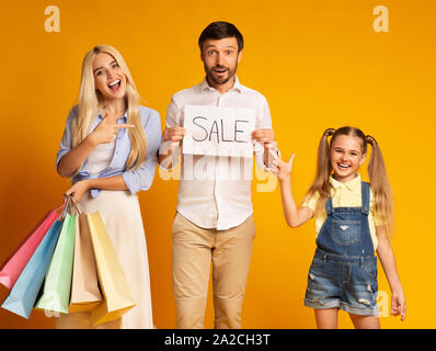 Montrant la famille Sale Sign Holding Shopping Bags Standing In Studio Banque D'Images