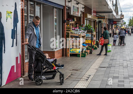 En attente de l'Homme avec enfant en poussette, High Street, West Bromwich, West Midlands, Royaume-Uni. Banque D'Images