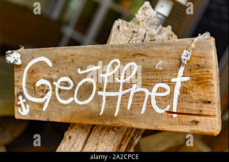 Conseil sur un poste en bois en face d'une boutique avec le mot "geoeffnet" - c'est l'allemand pour "ouvrir". Banque D'Images