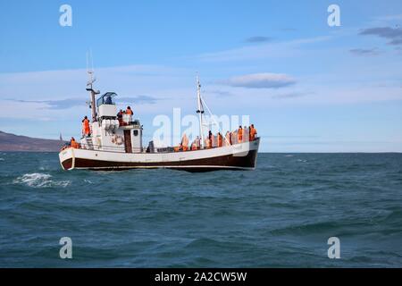 Húsavík, Islande - 25 septembre 2019 : les touristes dans des combinaisons orange partir en mer sur le bateau Husavik pour l'observation des baleines. Banque D'Images