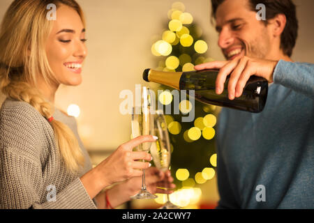 Man pouring champagne dans des verres, célébrer Noël avec ma femme Banque D'Images