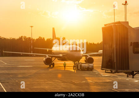 Avion de passagers au cours de repousser l'opération, l'aéroport le soir au coucher du soleil. Banque D'Images