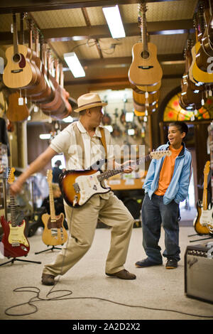 Grand-père et petit-fils en magasin à jouer de la guitare Banque D'Images