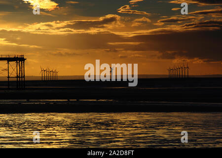 Coucher de soleil sur la mer du Nord avec des silhouettes d'éoliennes et d'une jetée, Dharamsala, North Yorkshire, Angleterre, Royaume-Uni. Banque D'Images