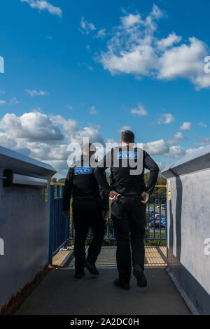 Deux agents de la police britannique des Transports d'hommes en uniforme de la fonction passerelle de franchissement de l'arrière. Vue arrière deux hommes ensoleillé avec ciel bleu Banque D'Images