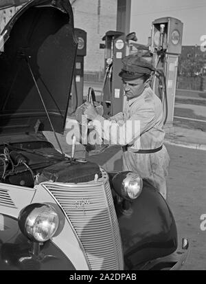 Der freundliche Tankwart an der Tankstelle Esso füllt Kühlwasser nach Deutschland, 1930er Jahre. Un préposé de station de remplissage remplissage facile l'échange de chaleur de l'eau, l'Allemagne des années 1930. Banque D'Images