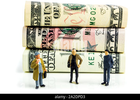 Miniatures de businessmen standing in front of american dollar billets et prendre des décisions économiques sur fond blanc Banque D'Images