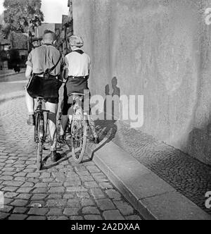 Hitlerjunge ein und ein Mädel BDM auf Ihren Fahrrädern in einer Gasse à Braunschweig, Deutschland 1930 er Jahre. Une jeunesse d'Hitler et une fille BDM sur leur bicyclette dans une ruelle de Braunschweig, Allemagne 1930. Banque D'Images