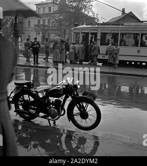 Un Straßenbahnhaltestelle von Menschen im Regen à Braunschweig, Deutschland 1930 er Jahre. Les gens à un tram dans la pluie à Braunschweig, Allemagne 1930. Banque D'Images