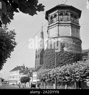 Der am Schloßturm mit der katholischen Kirche Burgplatz St Lambertus im Hintergrund à Düsseldorf, Deutschland 1930er Jahre. Urbangut tour à Burgplatz avec l'Église catholique église Lambert's en arrière plan à Duesseldorf, Allemagne 1930. Banque D'Images