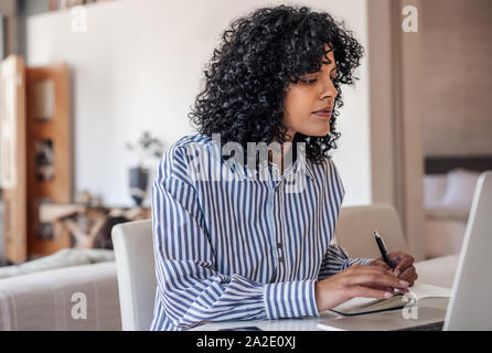 Jeune femme entrepreneur travaillant à domicile sur un ordinateur portable Banque D'Images