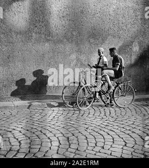 Hitlerjunge ein und ein Mädel BDM auf Ihren Fahrrädern in einer Gasse à Braunschweig, Deutschland 1930 er Jahre. Une jeunesse d'Hitler et une fille BDM sur leur bicyclette dans une ruelle de Braunschweig, Allemagne 1930. Banque D'Images