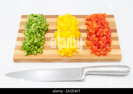 Rouge, vert et jaune haché poivrons doux sur une planche à découper en bois et un couteau de coupe Banque D'Images