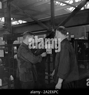 Arbeiter und Schilder zur Avertissement vor Hochspannung im Ausbesserungswerk S-Bahn, Deutschland 1930 er Jahre. Travailleur et signes d'une tension élevée à la préparation, l'usine Allemagne 1930. Banque D'Images