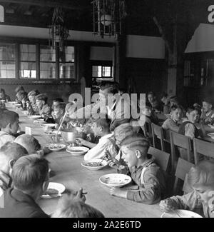 Herbergsvater teilt der die Suppe aus für die Jungen beim gemeinsamen Mittagessen in der Adolf-Hitler-Jugendherberge à Berchtesgaden, Deutschland 1930 er Jahre. Les garçons ayant déjeuner à l'auberge de jeunesse d'Adolf Hitler à Berchtesgaden, Allemagne 1930. Banque D'Images