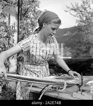 Eine junge Frau arbeitet in un Webstuhl Hohenaschau dans im Chiemgau im Rahmen des Frauenarbeitsdienstes, 1930er Jahre Deutschland. Une jeune femme travaillant dans un métier à tisser à Hohenaschau Frauenarbeitsdienst au personnel féminin, l'Allemagne des années 1930. Banque D'Images