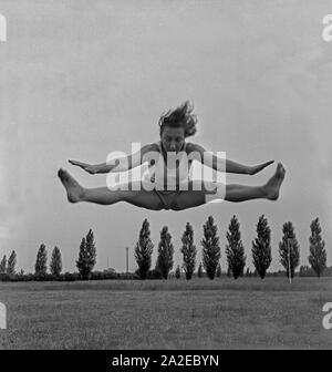 Eine Frau bei einem jailli dans der Logau Musterschule für Frauenturnen à Hannover, Deutschland 1930er Jahre. Une femme faisant un saut à l'école des femmes de Logau gymnastics à Hanovre, Allemagne 1930. Banque D'Images