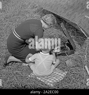 Eine junge Frau und ein kleiner Junge hören beim zelten Musik von einem Electrola Koffer 106 Grammophon, Deutschland 1930er Jahre. Une femme et un petit garçon écoute de musique joué par un gramophone Electrola Koffer 106, tandis que le camping, Allemagne 1930. Banque D'Images