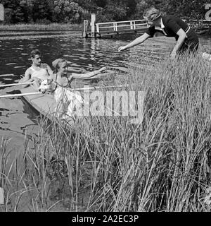 Ein Mann und eine Frau in einem Klepper Faltboot Am Ufer und werden von einer weiteren voit Frau empfangen, Deutschland 1930er Jahre. Un homme et une femme dans un bateau pliant Klepper sont accueillis par une autre femme sur la rive d'un lac, l'Allemagne des années 1930. Banque D'Images