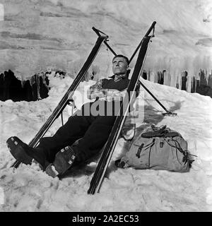 Un Skiurlauber hat sich aus seinen Sitz und einen skieur gebaut macht eine Pause, Deutschland 1930 er Jahre. Un tourisme de ski construit un siège de ses skis et d'avoir une pause maintenant, l'Allemagne des années 1930. Banque D'Images