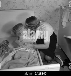 Eine Mutter bringt ihren Sohn ins Bett und gibt ihm einen Gutenachtkuss, 1930er Jahre Deutschland. Une mère amène son fils au lit et l'embrasser une bonne nuit, l'Allemagne des années 1930. Banque D'Images