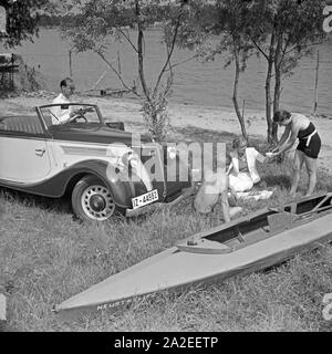 Für den Werbefoto Personenkraftwagen Ford Eifel mit einem Paar und mit Paddelboot Paddlern, Deutschland 1935. Photo commerciale pour le passager car Ford Eifel avec couple et de canoë et des pagayeurs, Allemagne 1935. Banque D'Images