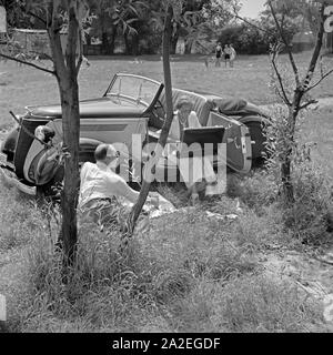 Für den Werbefoto Personenkraftwagen Ford Eifel mit einem Paar mit Picknickkoffer, Deutschland 1935. Photo commerciale pour le passager car Ford Eifel avec couple et panier pique-nique, Allemagne 1935. Banque D'Images