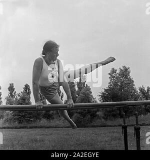 Eine Frau bei einer Übung suis Stufenbarren dans der Logau Musterschule für Frauenturnen à Hannover, Deutschland 1930er Jahre. Une femme faisant un exercice à la barres asymétriques à l'école des femmes de Logau gymnastics à Hanovre, Allemagne 1930. Banque D'Images