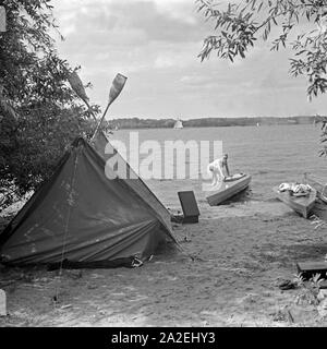 Werbefoto für das Zelt und Klepper Faltboot : eine junge Frau holt ein Boot am Strand von voit une terre, Deutschland 1930 er Jahre. Un foldboat publicité für Klepper et tente : une jeune femme de prendre le bateau sur la rive d'un lac, l'Allemagne des années 1930. Banque D'Images