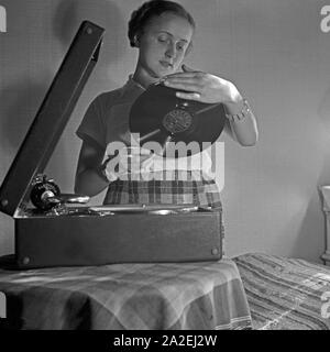 Eine junge Frau mit einem Electrola Koffer für den Hausgebrauch 106 Grammophon, Deutschland 1930 er Jahre. Une jeune femme avec un gramophone valise Koffer Electrola 106 pour l'usage à la maison, de l'Allemagne des années 1930. Banque D'Images