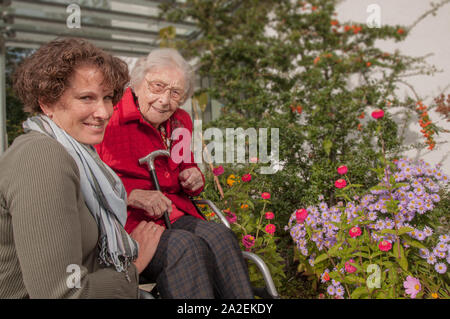 Vieille dame avec fauteuil roulant et les femmes soignant heureux dans le jardin Banque D'Images