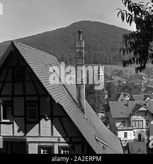 Blick auf den Turm der Klosterkirche hinter einem Fachwerkhaus in Herrenalb im Schwarzwald, Deutschland 1930er Jahre. Vue de le beffroi de la cathédrale derrière une maison à colombages à Bellingen en Forêt Noire, Allemagne 1930. Banque D'Images