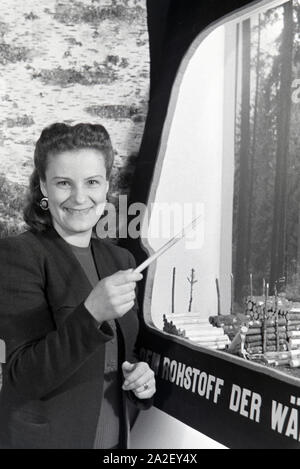 Eine der Leipziger Frühjahrsmesse Besucherin vor einem Modell der Rohstoffnutzung Holz, Deutschland 1941. Un visiteur de la Leipziger Frühjahrsmesse en face d'un modèle de l'utilisation de la matière première bois, Allemagne 1941. Banque D'Images